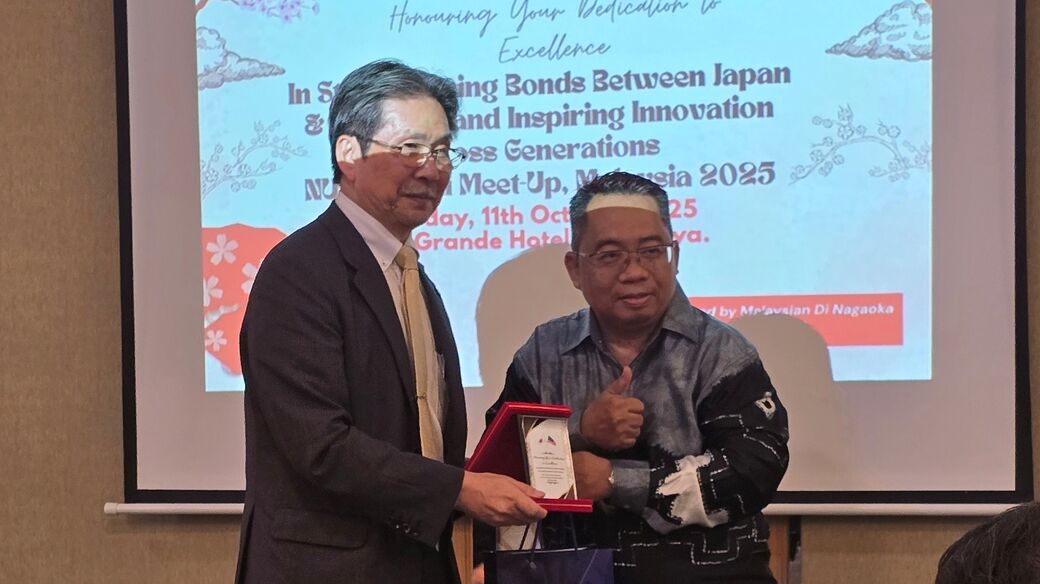 鎌土学長とアルバイン氏が感謝の気持ちを込めて記念品を交換